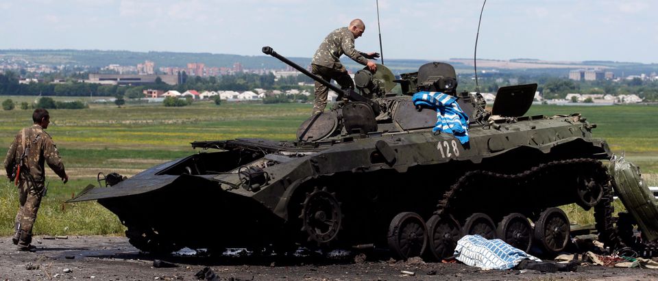 Ukrainian soldiers check a destroyed armoured vehicle at a Ukrainian Army checkpoint in the outskirts of the eastern Ukrainian town of Slaviansk