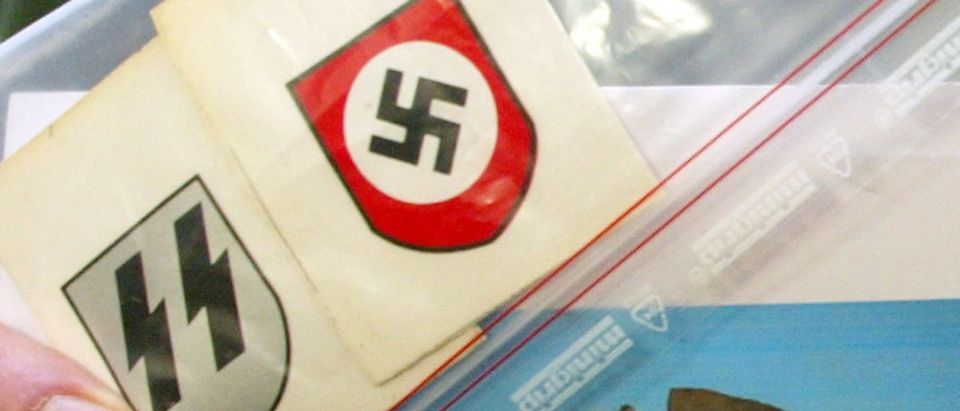 POLICE OFFICER DISPLAYS CONFISCATED NAZI INSIGNIA AND A PHOTO OFEXPLOSIVES IN MUNICH.