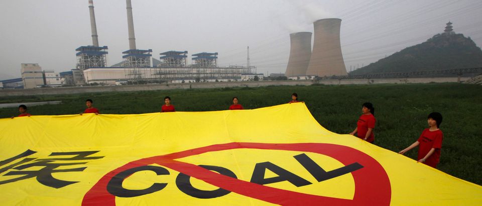 Greenpeace activists hold a banner during a protest against carbon emissions in front of a coal-fired power station west of Beijing