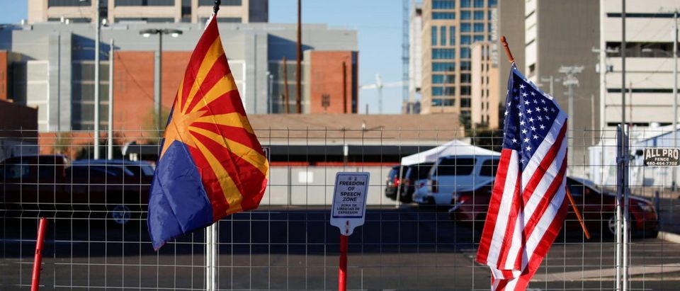 A U.S. flag and an Arizona state flag hang from a fence marking the "Freedom of speech zone" at the Maricopa County Tabulation and Election Center (MCTEC) after the 2020 U.S. presidential election was called for Democratic candidate Joe Biden, in Phoenix