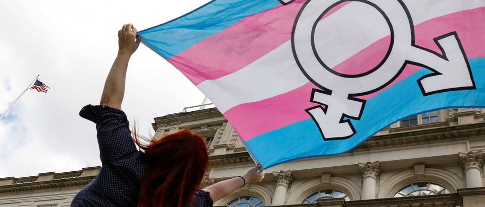 A person holds up a flag during rally to protest the Trump administration's reported transgender proposal to narrow the definition of gender to male or female at birth in New York
