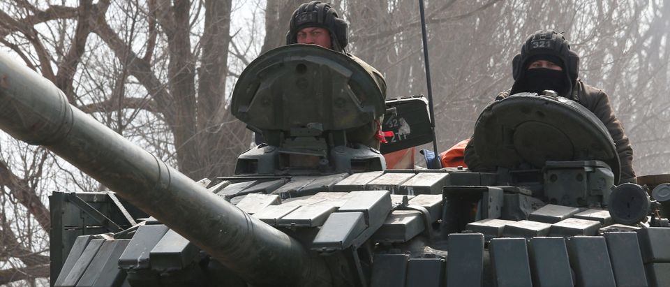 Service members of pro-Russian troops in uniforms without insignia are seen atop of a tank outside Volnovakha
