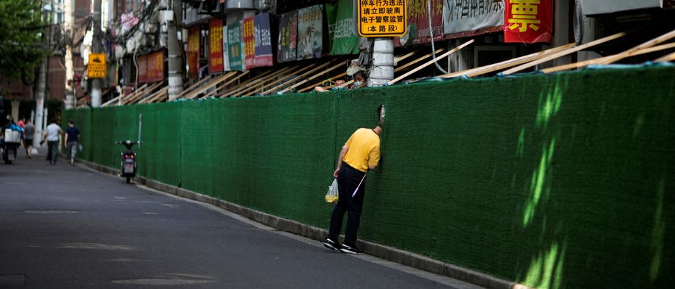 A man looks in through a gap in a barrier in a residential area, after the lockdown placed to curb the coronavirus disease (COVID-19) outbreak was lifted in Shanghai, China June 7, 2022. (REUTERS/Aly Song)