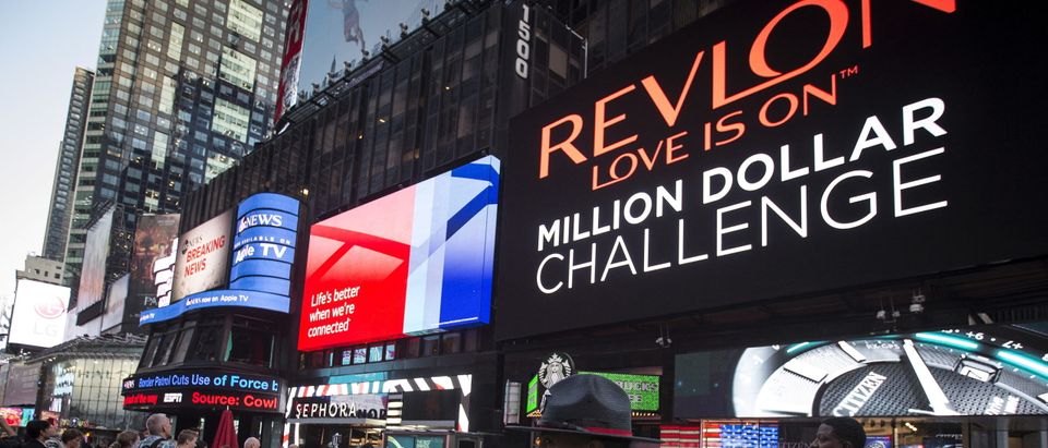 FILE PHOTO: A Public Safety officer keeps watch as people stand in front of a billboard owned by Revlon that takes their pictures and displays them in Times Square in the Manhattan borough of New York