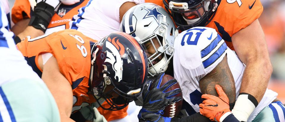 Sep 17, 2017; Denver, CO, USA; Dallas Cowboys running back Ezekiel Elliott (21) is tackled by Denver Broncos defensive end Adam Gotsis (99) and Denver Broncos defensive end Derek Wolfe (95) in the first quarter at Sports Authority Field at Mile High. Mandatory Credit: Ron Chenoy-USA TODAY Sports via Reuters
