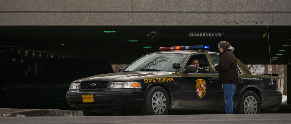 Woman speaks with a Maryland State Trooper as a photographer perches above the parking garage after a shooting at the shopping mall in Columbia