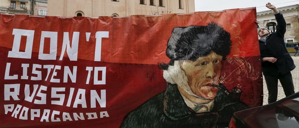 An activist holds a banner with a portrait of Dutch artist Vincent van Gogh as he demonstrates outside the Dutch embassy in Kiev, Ukraine