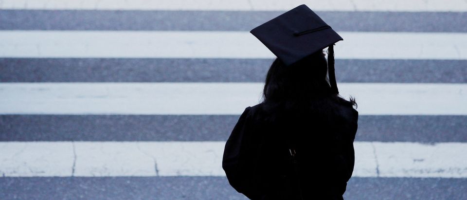 FILE PHOTO: A graduating student waits to cross the street before Commencement Exercises at MIT in Cambridge