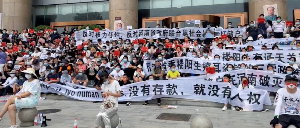 Demonstrators hold banners during a protest over the freezing of deposits by rural-based banks, outside a People's Bank of China building in Zhengzhou, Henan province, China July 10, 2022, in this screengrab taken from video obtained by Reuters. (Reuters)