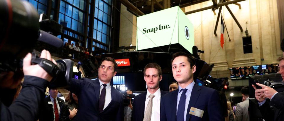 Snap co-founders Evan Spiegel and Bobby Murphy walk on the floor before the opening bell of the New York Stock Exchange (NYSE) with NYSE Group President Thomas Farley shortly before the company's IPO in New York, U.S., March 2, 2017. Brendan McDermid/REUTERS