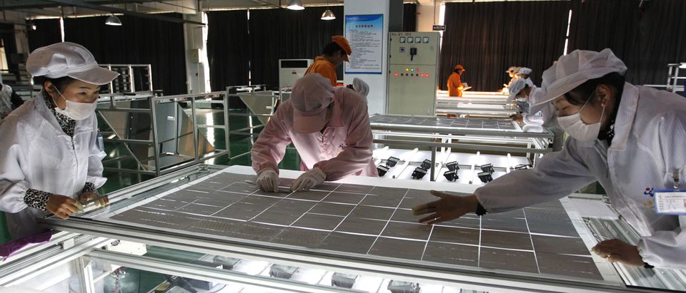 Chinese workers inspect a solar panel at